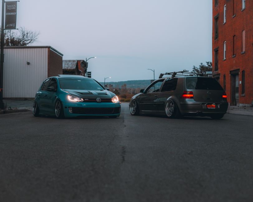 Two Volkswagen cars parked on a city street during twilight